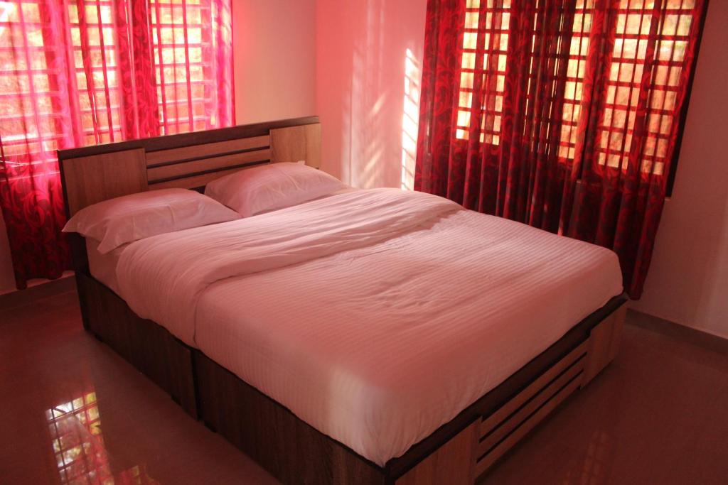 a bed in a bedroom with red curtains at Wayanad Days in Mananthavady