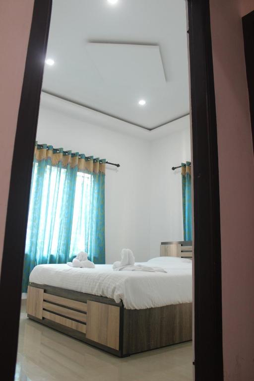 a bedroom with a large bed with blue curtains at Wayanad Days in Mananthavady