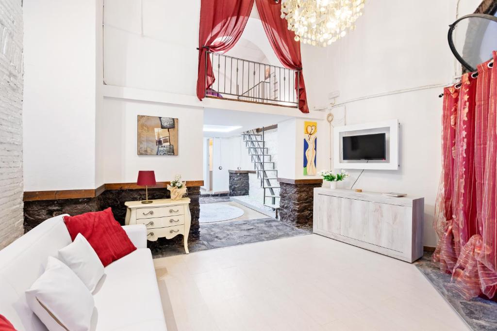 een woonkamer met een witte bank en een tv bij Charming Sicilian Loft in Catania