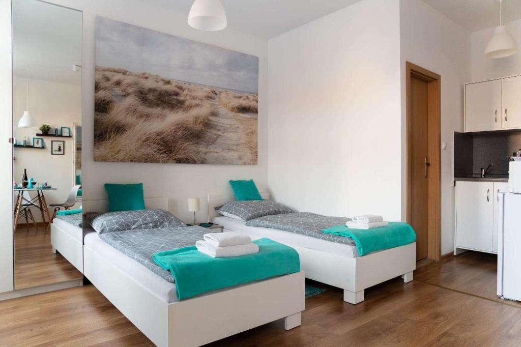 a bedroom with two beds and a kitchen with a table at Jonas Apartments - Great Location near Bratislava City Center in Bratislava