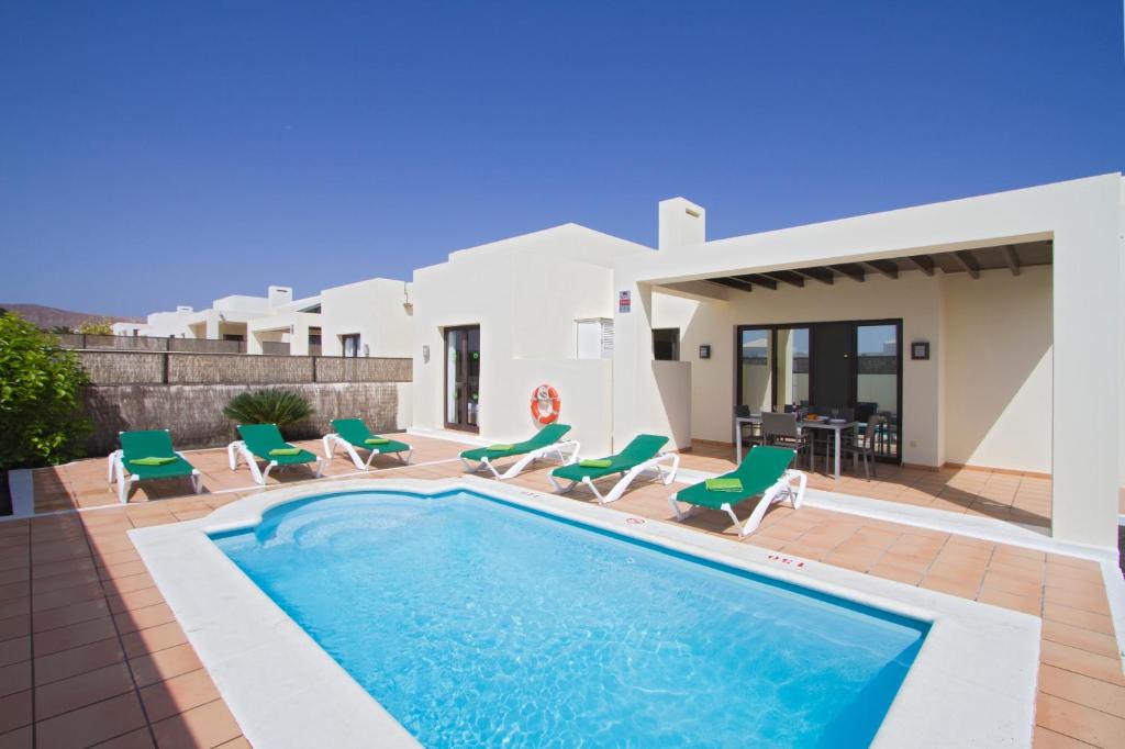 Willa z basenem i zielonymi krzesłami w obiekcie Ereza Villas Las Buganvillas w mieście Playa Blanca