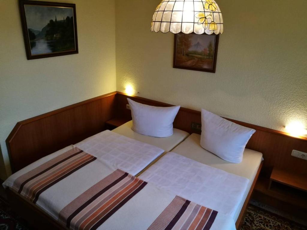 - une chambre dotée d'un lit avec deux oreillers et une lampe dans l'établissement Pension Schulze, à Oranienbaum-Wörlitz