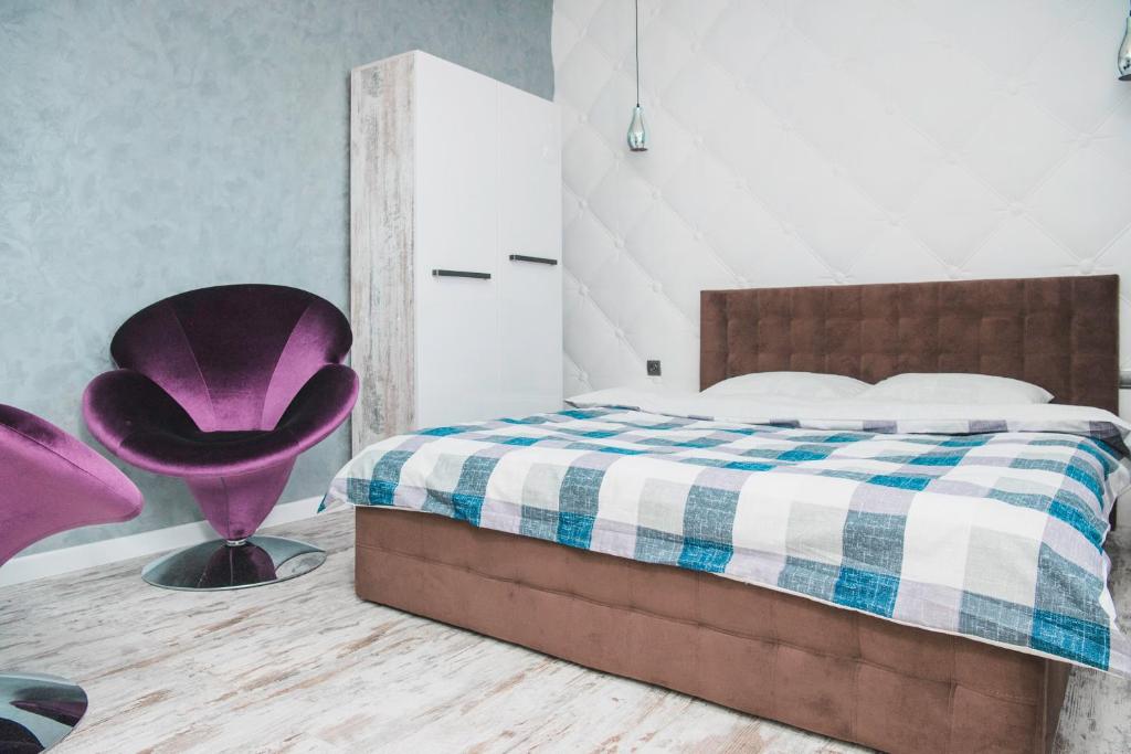 a bedroom with a bed and a purple chair at Апартаменти в центрі Львова in Lviv