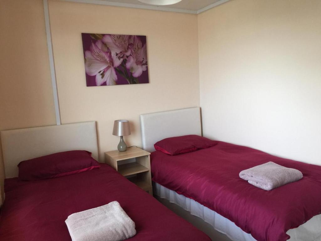 twee bedden in een kamer met rode lakens bij Laughing Buddha Guesthouse in Uddingston