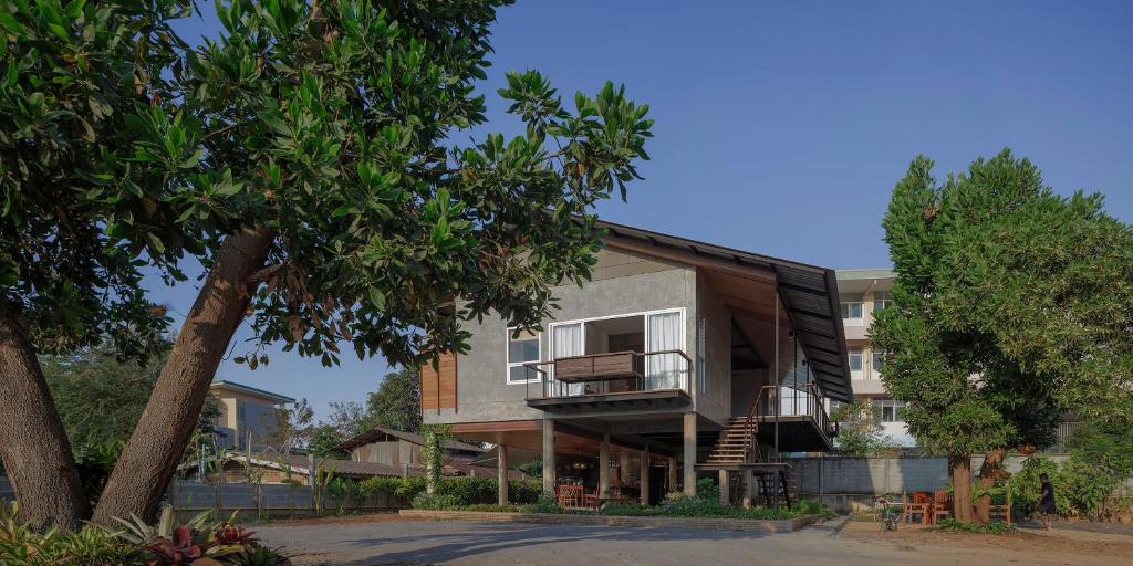 a house with a balcony and a tree at Baan Lek Villa in Chanthaburi