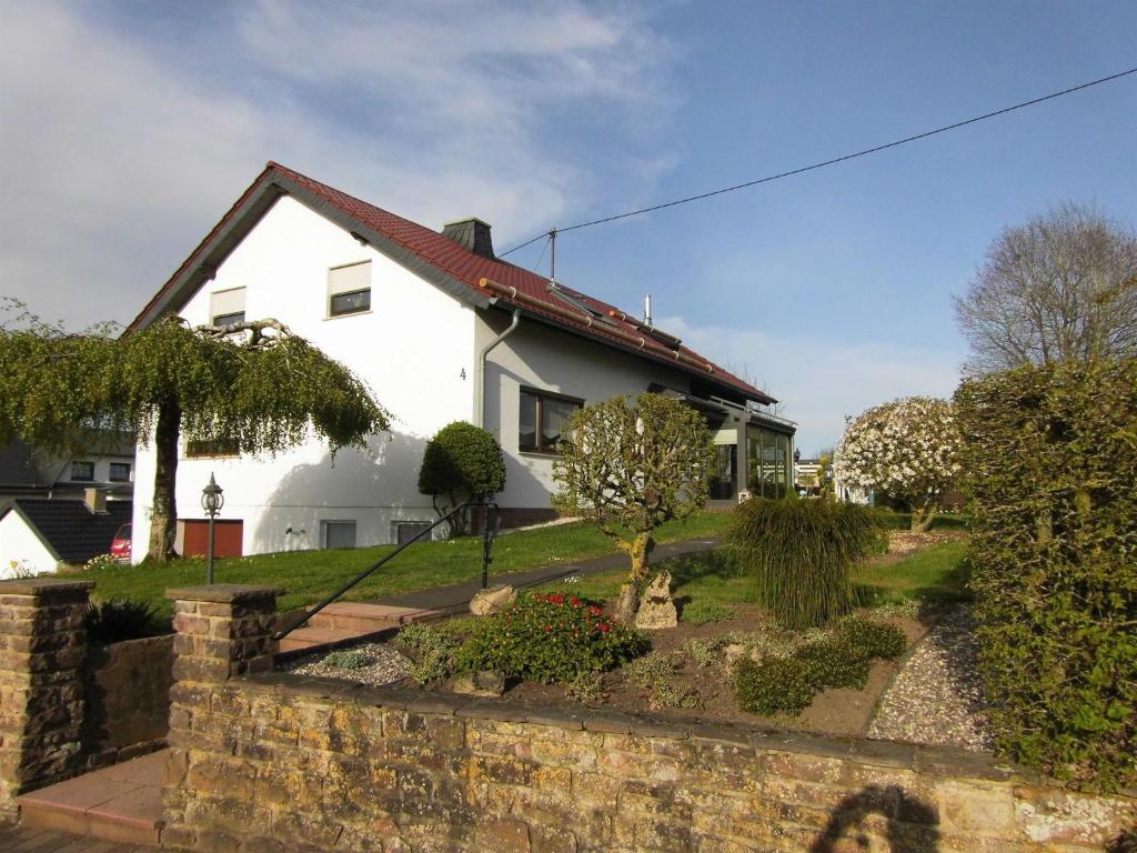 a white house with a stone wall and a yard at Ferienwohnung Elgas in Habscheid