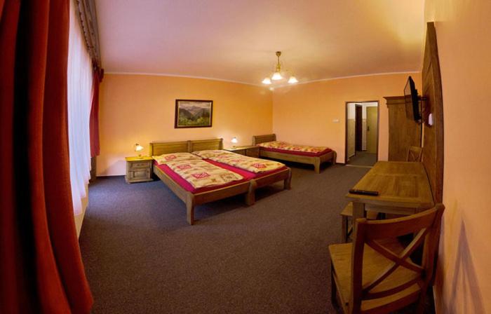ein Hotelzimmer mit 2 Betten und einem Tisch in der Unterkunft Hotel Ranč u Edyho in Námestovo