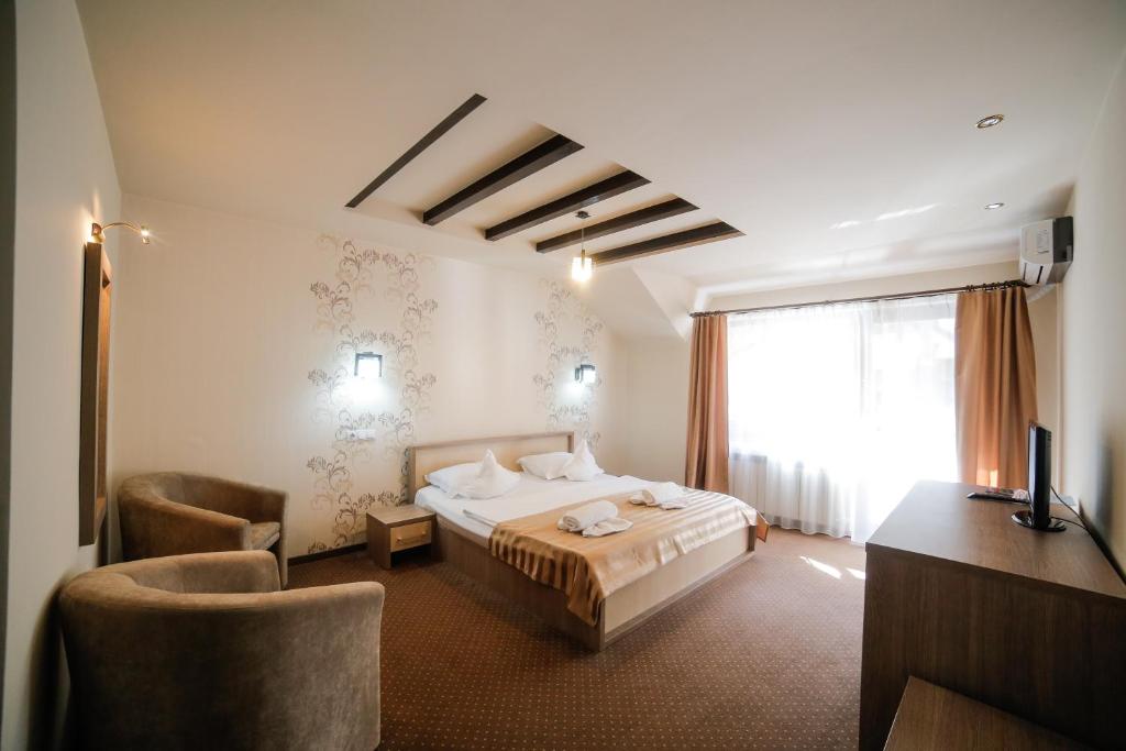 Habitación de hotel con cama, escritorio y TV. en Pensiunea JOJO, en Băile Herculane