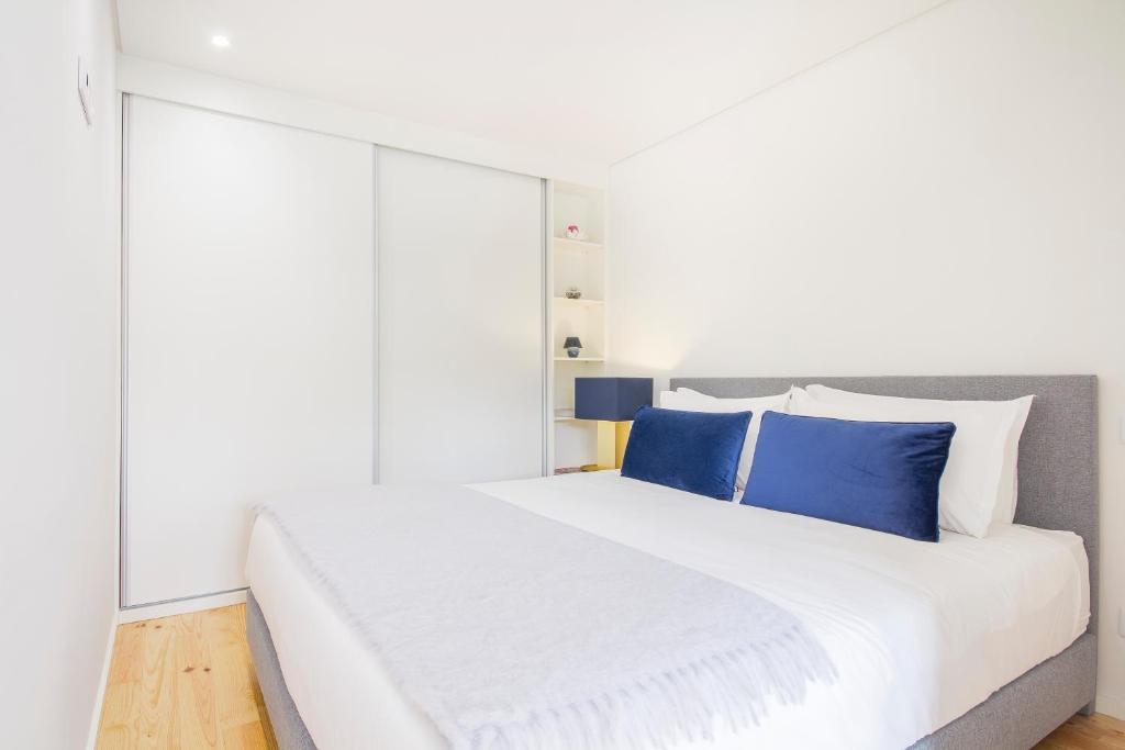 a bedroom with a large white bed with blue pillows at São Bento Hill View in Porto