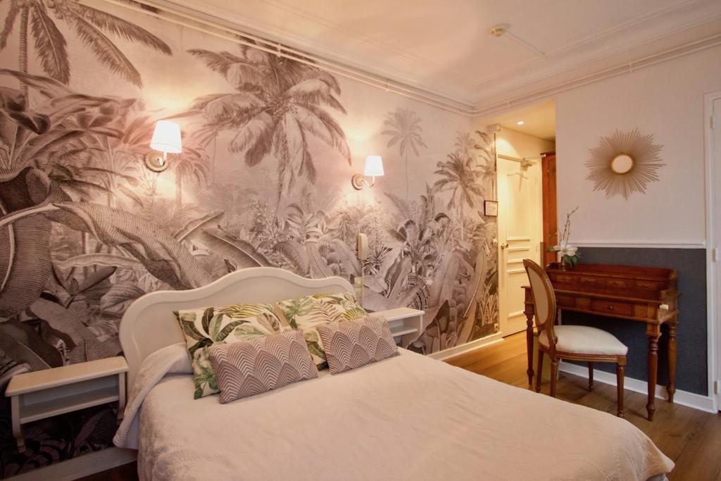 a bedroom with a bed with a mural of palm trees at Hôtel Chopin in Paris