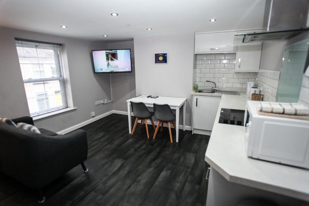 a kitchen with a table and a tv on the wall at No 4 New Inn Apartments in Newark upon Trent