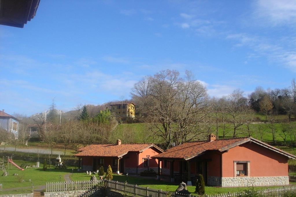 uma casa num campo com um edifício ao fundo em Apartamentos Rurales La Granda em Cangas de Onís