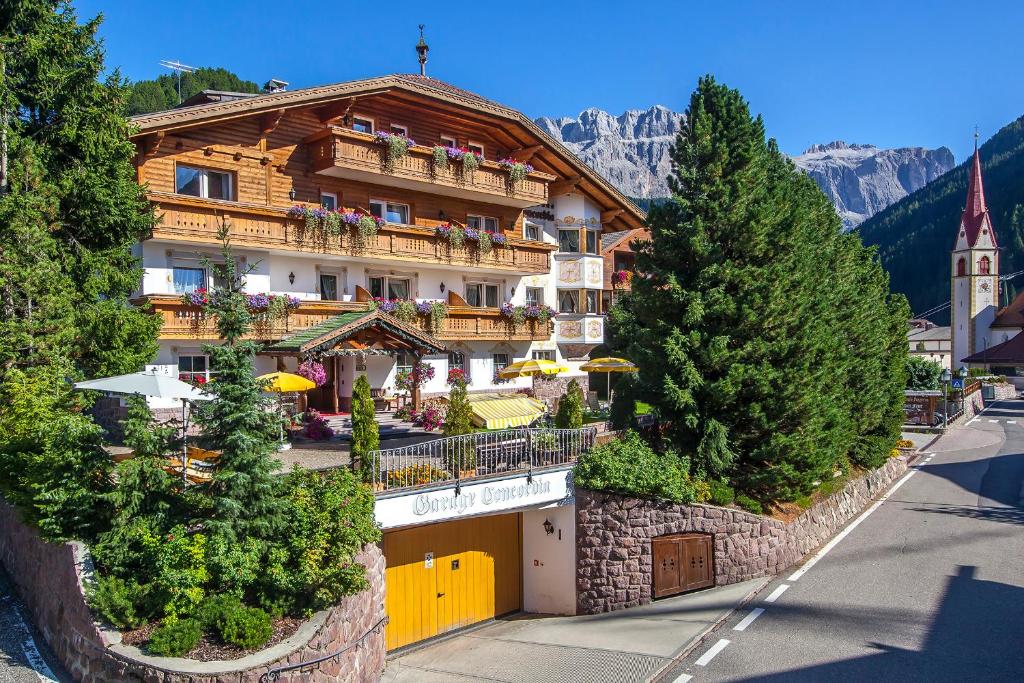 セルヴァ・ディ・ヴァル・ガルデーナにあるHotel Garni Concordia - Dolomites Homeの木々が目の前に広がるバルコニー付きの建物