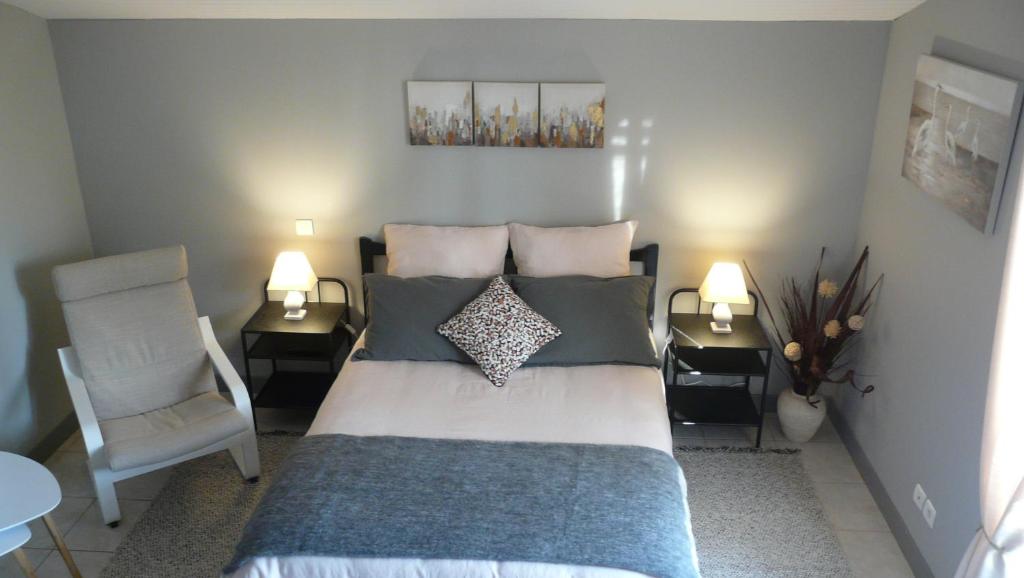 a bedroom with a bed with pillows and a chair at Au Bras d'Argent in Berthez