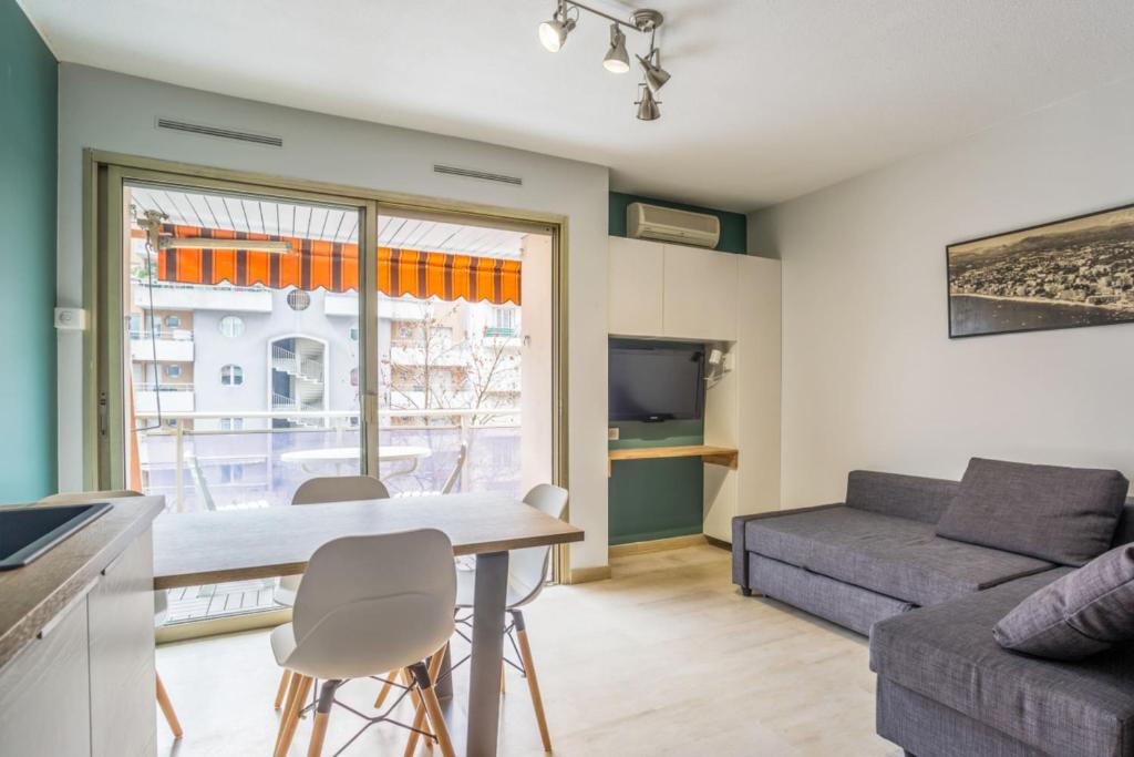 un salon avec une table, des chaises et un canapé dans l'établissement Le Cocon Juanais - Welkeys, à Antibes