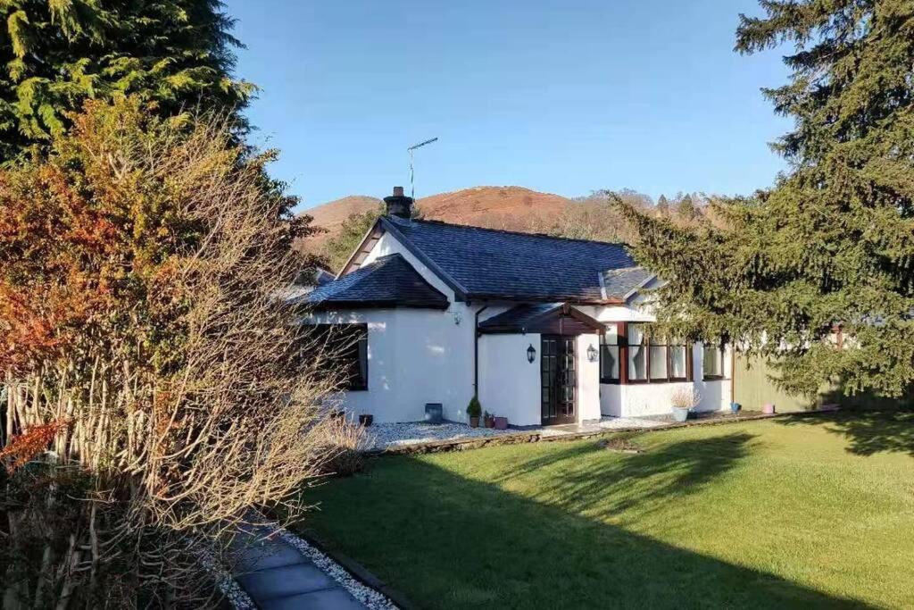 a small white house with a grass yard at Broomfield Cottage South Luss in Glasgow
