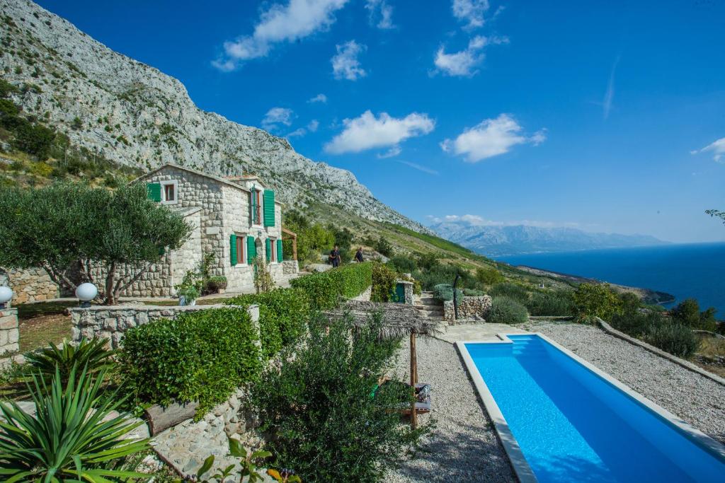 a house on the side of a mountain with a swimming pool at Dalmatian stone villa with pool in Lokva Rogoznica