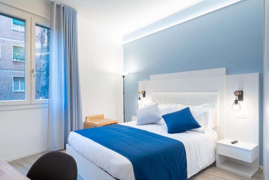 Un dormitorio blanco con una cama azul y una silla en Torri & Portici, en Bolonia