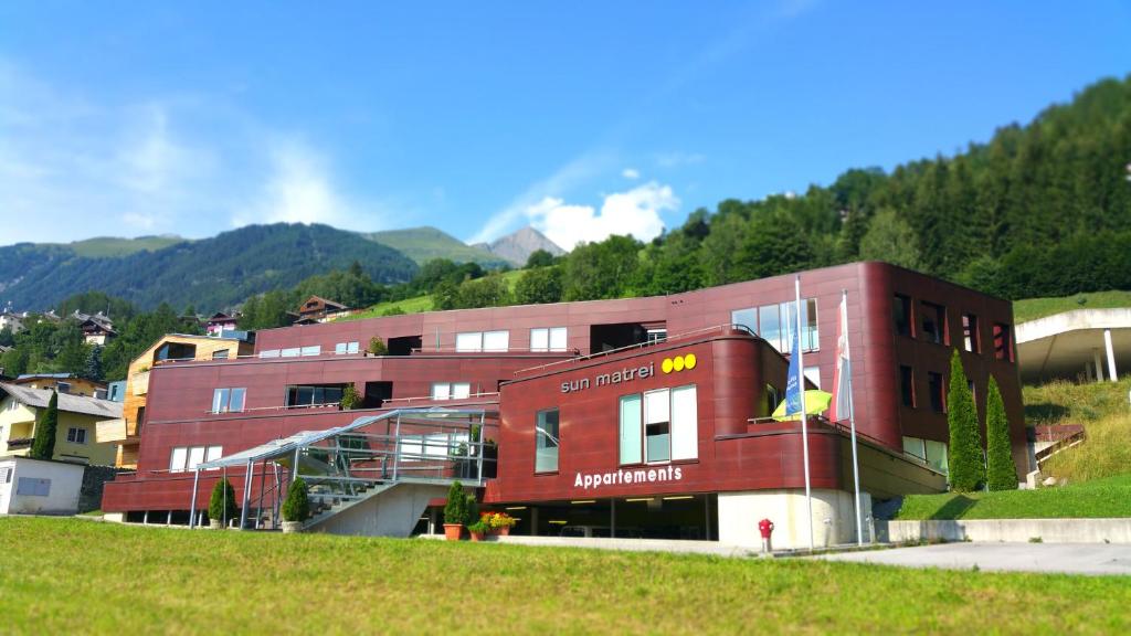 a large red building in front of a mountain at Sun Matrei Apartments in Matrei in Osttirol