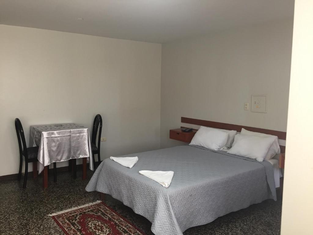 a bedroom with a bed and a table with a chair at Hotel Plazza in Chiclayo