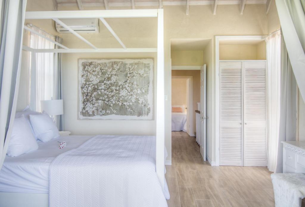 a bedroom with a white bed and a painting on the wall at West Rock Villas in Saint James