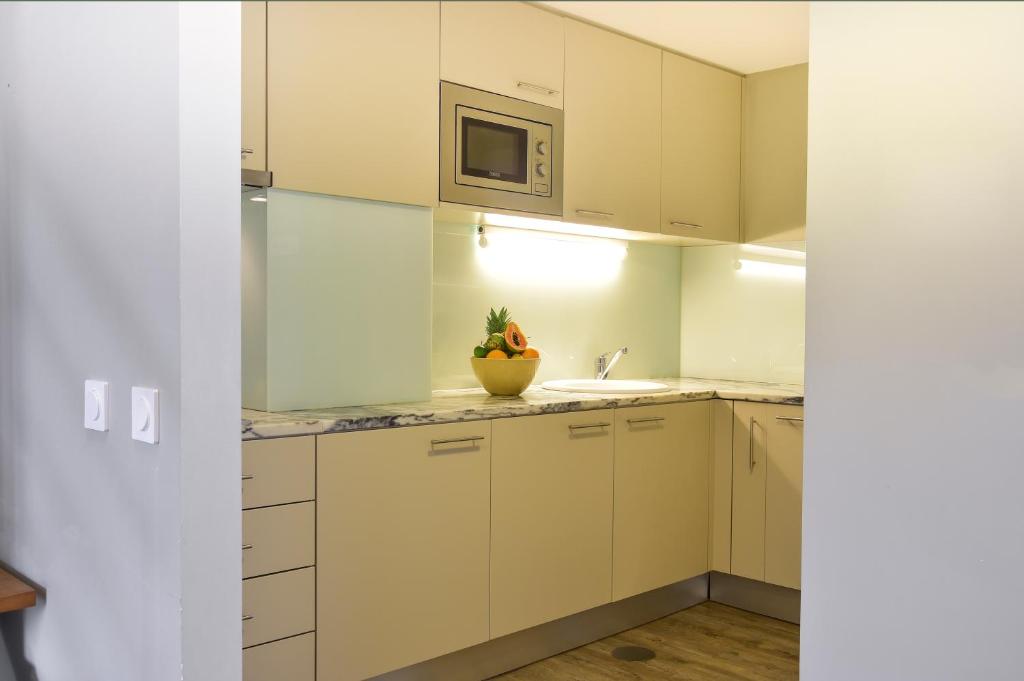 a kitchen with white cabinets and a sink and a microwave at Aqualuz Lagos by The Editory in Lagos