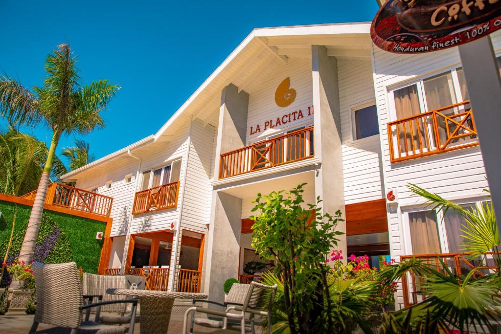 a white building with chairs and tables in front of it at La Placita Inn in West Bay