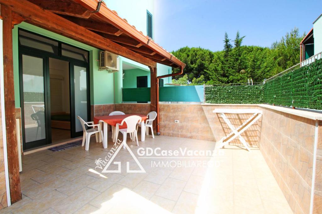トッレ・デル・オルソにあるGD Case Vacanza -Moderno con ampia veranda-のテラス、テーブルと椅子が備わるゲストハウスです。