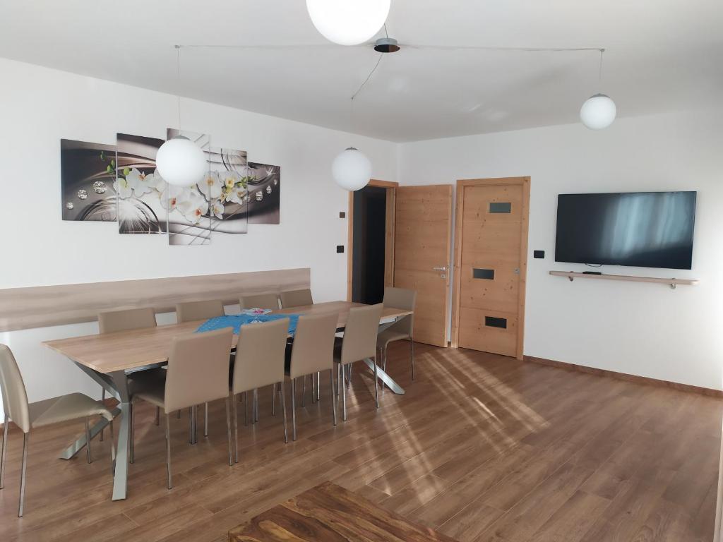 a dining room with a table and chairs and a flat screen tv at Appartamento DIAMANTE in Passo del Tonale