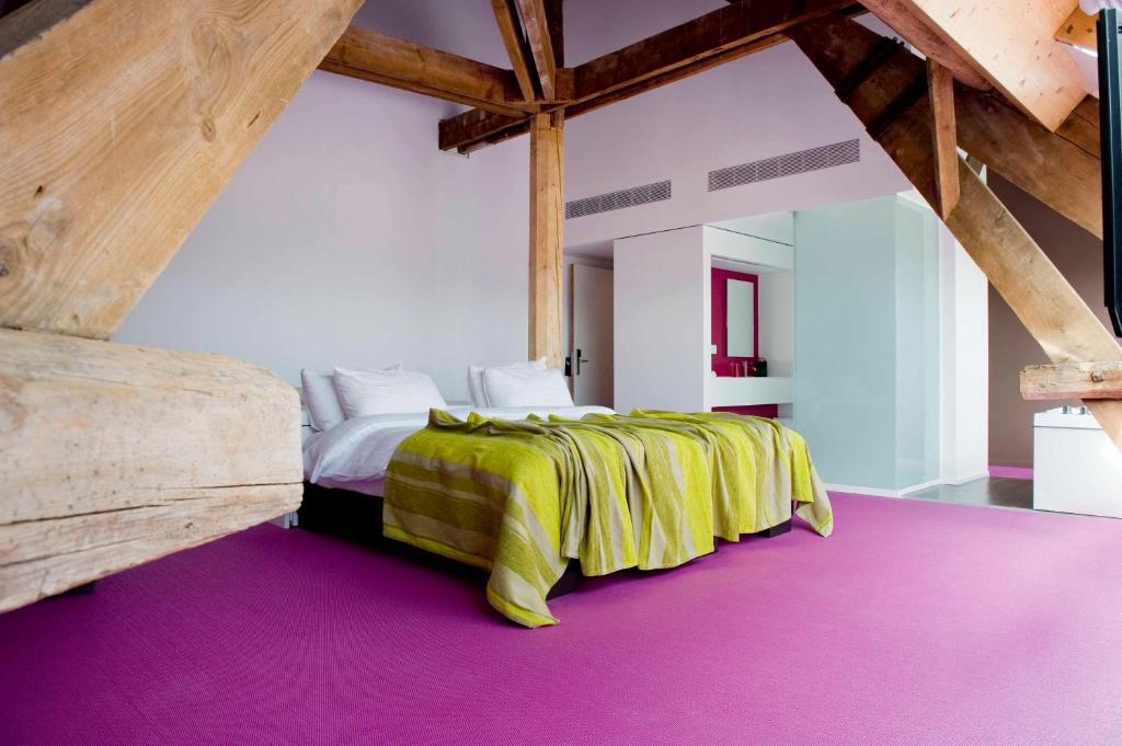 a bedroom with a bed with a green and yellow blanket at Eburon Hotel in Tongeren