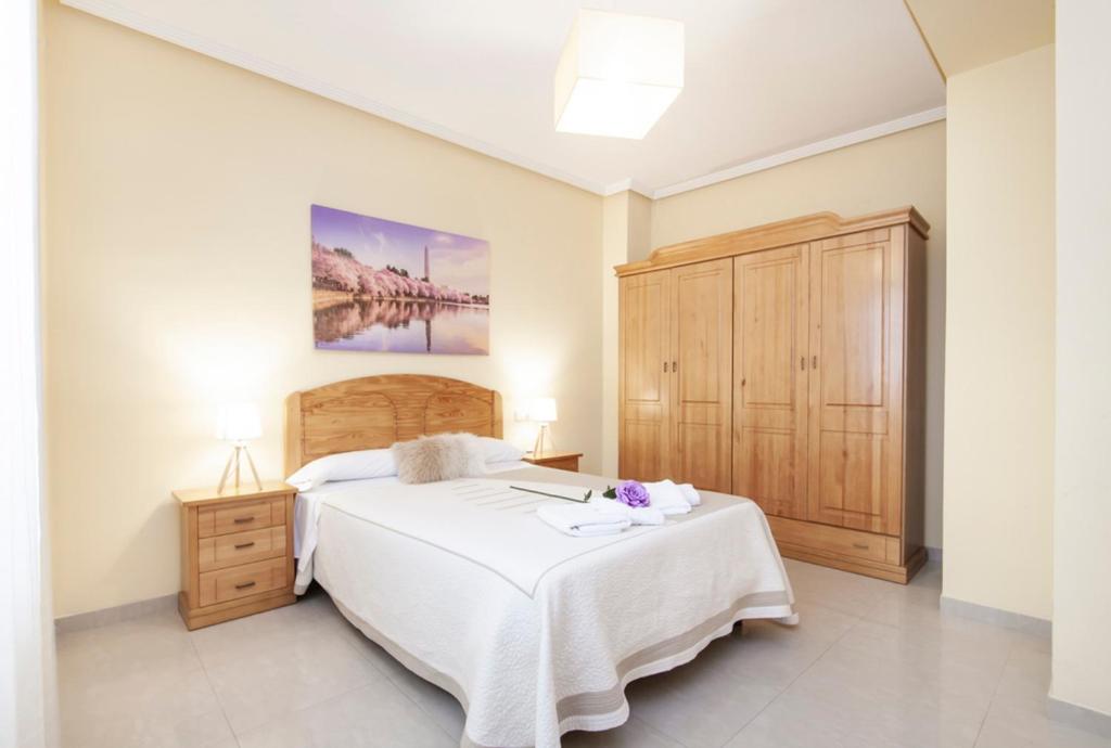 グラナダにあるApartamento en Granada Centroの白いベッドと木製キャビネット付きのベッドルーム1室が備わります。