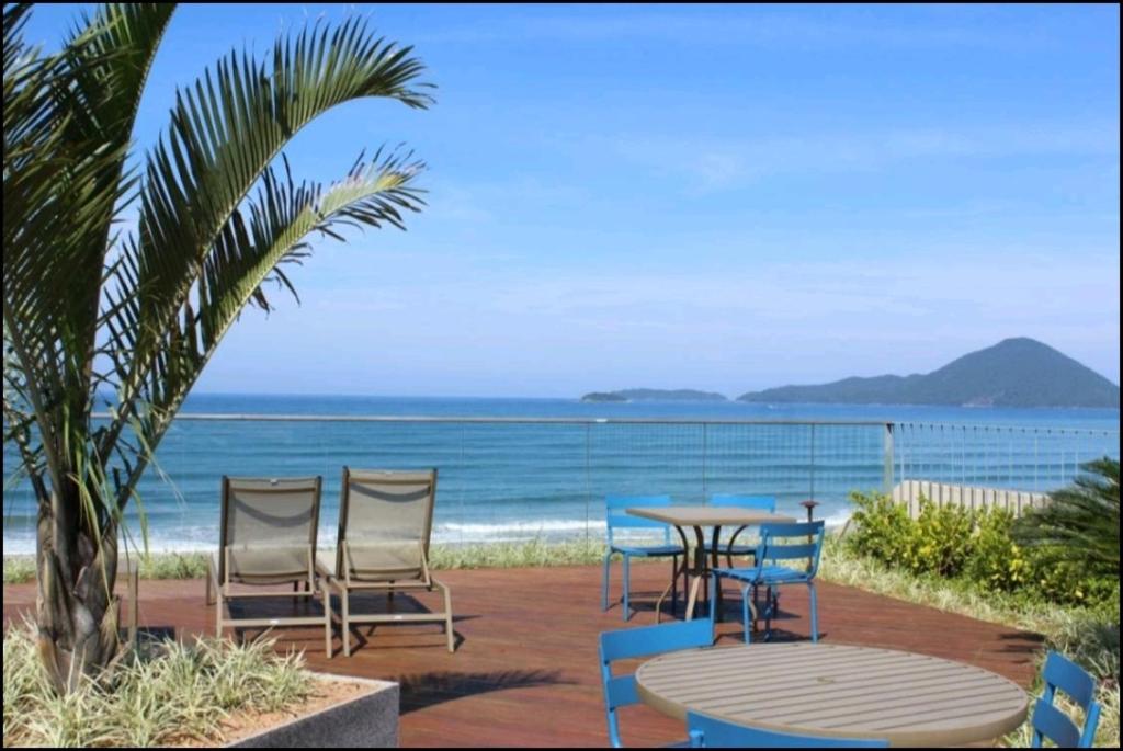a patio with a table and chairs and the ocean at Maravilhoso Apartamento Reserva DNA Ubatuba in Ubatuba
