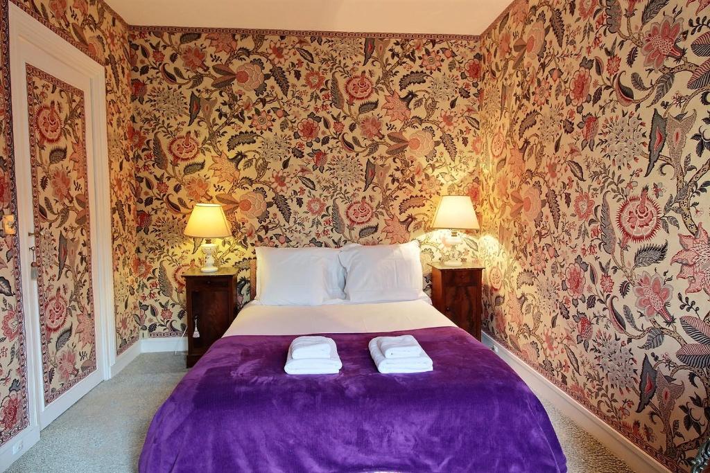 a bedroom with a purple bed with floral wallpaper at Parisian Home I 390 I 1 chambre I Odéon in Paris