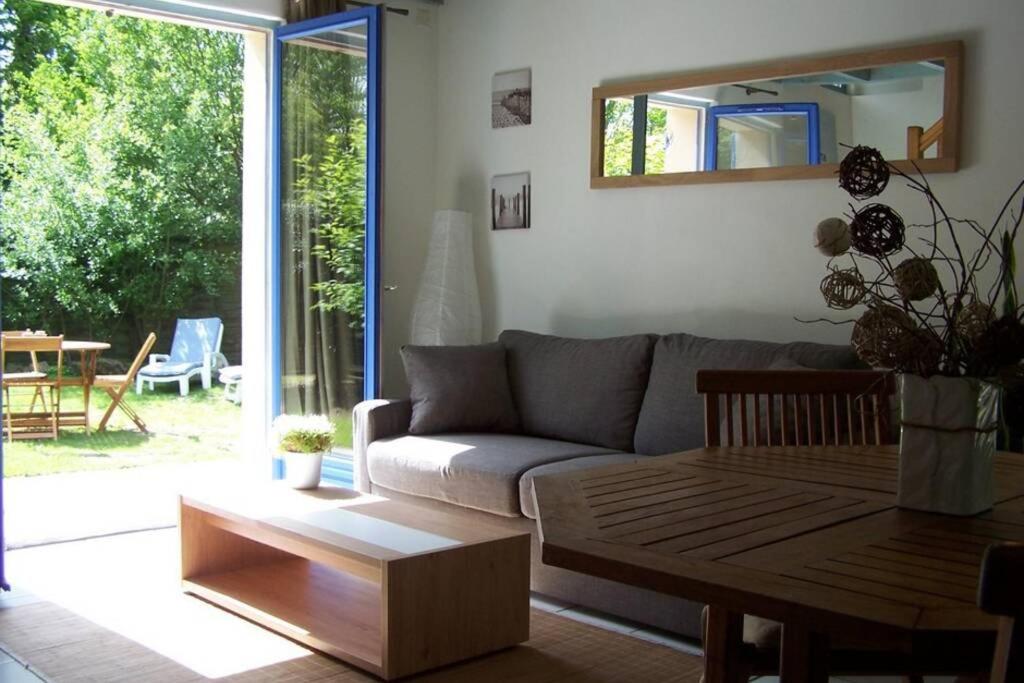 een woonkamer met een bank en een tafel bij Maison avec jardin clos. Animaux acceptés - Wifi - Proche plages de la Trinité sur Mer et Carnac in La Trinité-sur-Mer