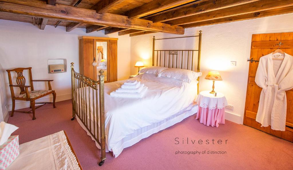 a bedroom with a large bed and a chair at Ballavere Cottage B&B in Colby