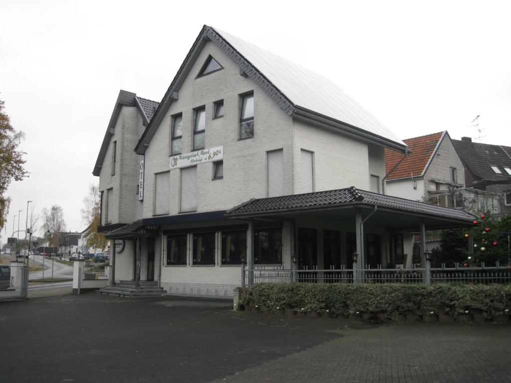 a large white building with a store on a street at Hotel Restaurant "Waldschänke" in Wassenberg