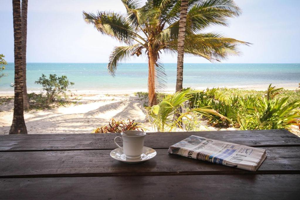 a cup of coffee and a newspaper on a table on the beach at Ocean Dream Villa in Ushongo Mabaoni