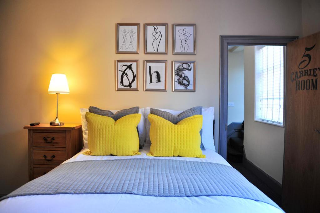 a bedroom with a bed with yellow pillows at The Herbalist Rooms in Retford