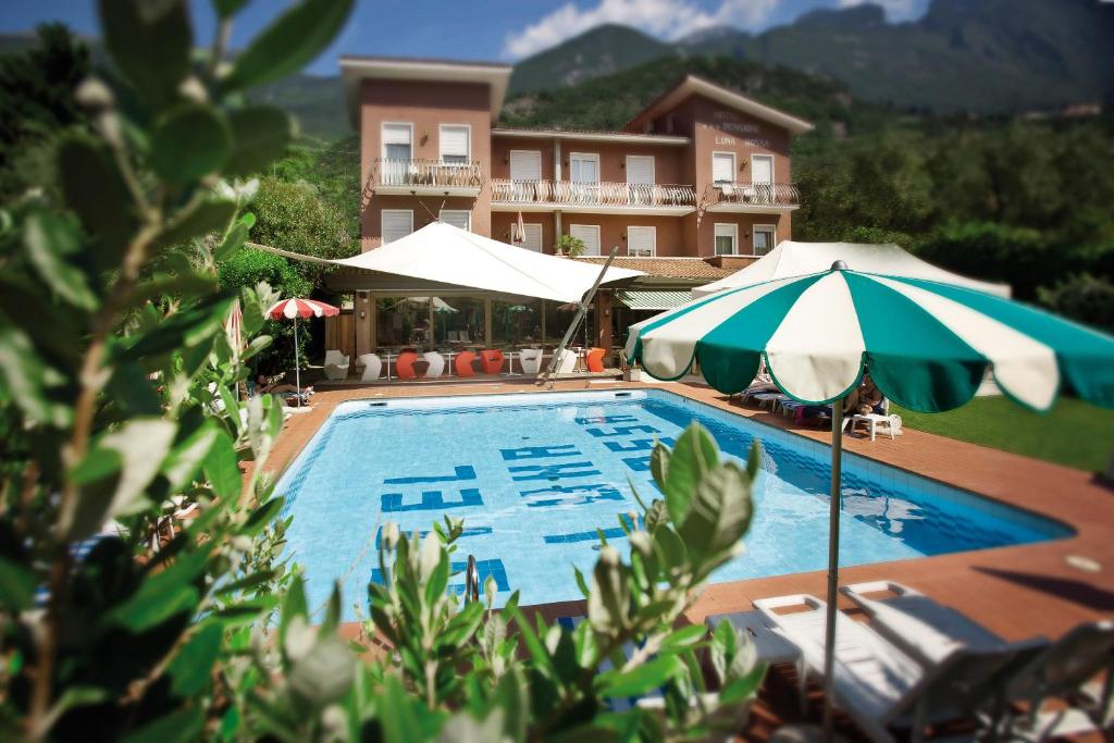 ein Pool mit zwei Sonnenschirmen neben einem Gebäude in der Unterkunft Ambienthotel Luna Rossa in Malcesine