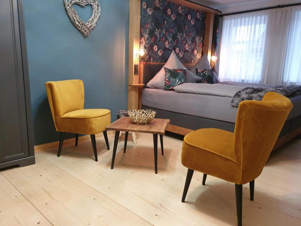 a bedroom with a bed and two chairs and a table at Pelikans Krone in Bad Sooden-Allendorf