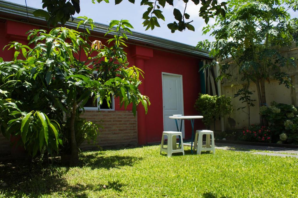 un tavolo e due sgabelli di fronte a una casa rossa di Rincón Colombiano a Yerba Buena