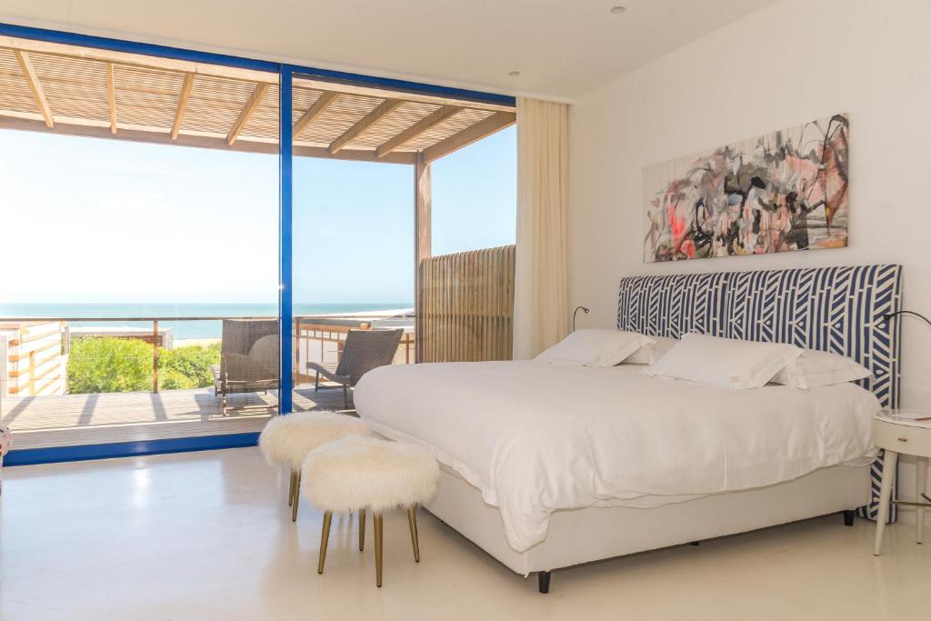 um quarto com uma cama branca e uma grande janela em Bahia Vik em José Ignacio
