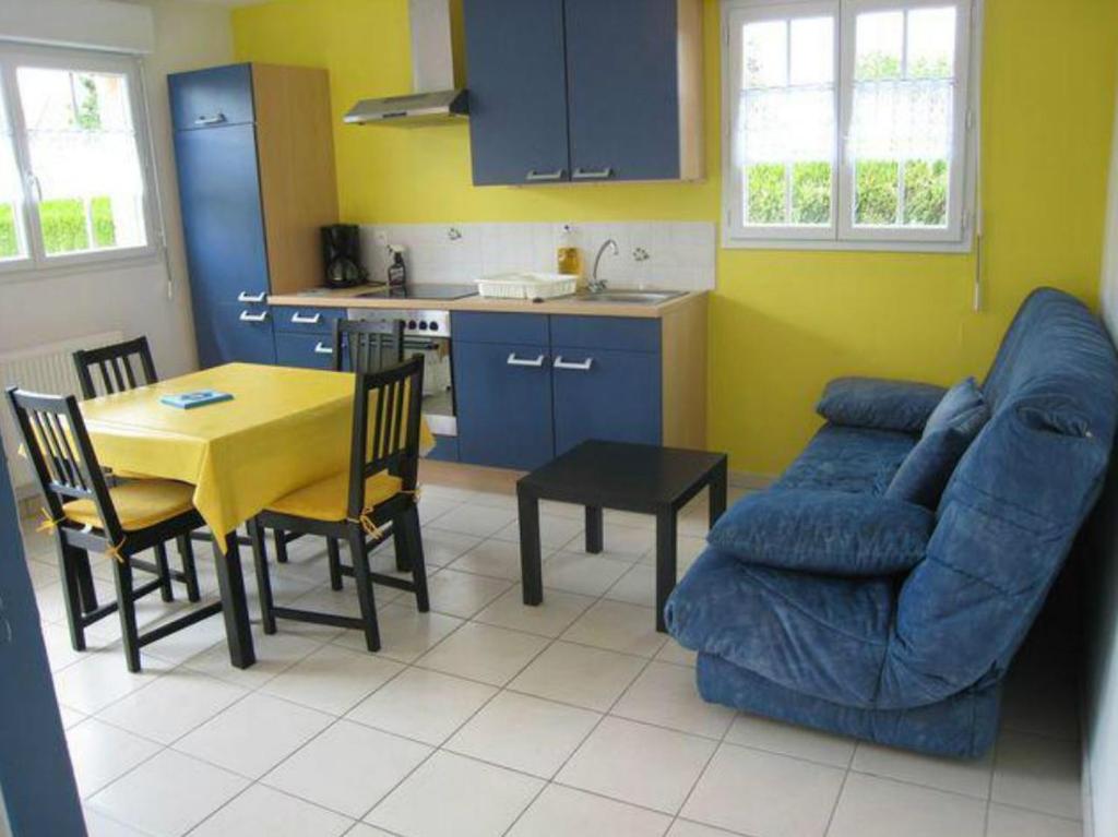 sala de estar con mesa y sofá azul en La Résidence des Fleurs, en Lecelles