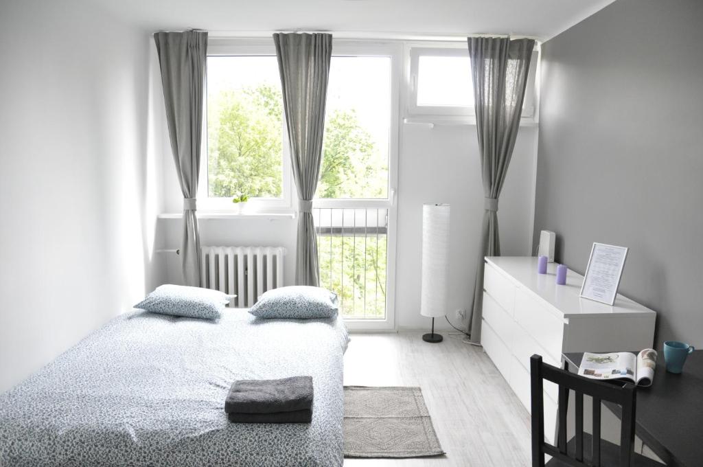 a white bedroom with a bed and a window at Mario Rooms in Warsaw