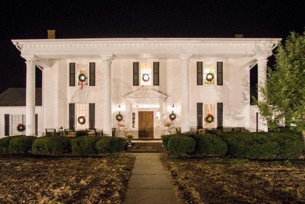 Una casa blanca con coronas de Navidad. en Historic Cedar Hill Mansion on Large Farm with Pool!, en Pleasant View