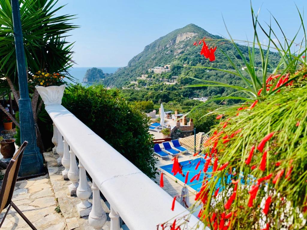 a white railing next to a swimming pool with a mountain at Ermones Ruby Villa in Vátos