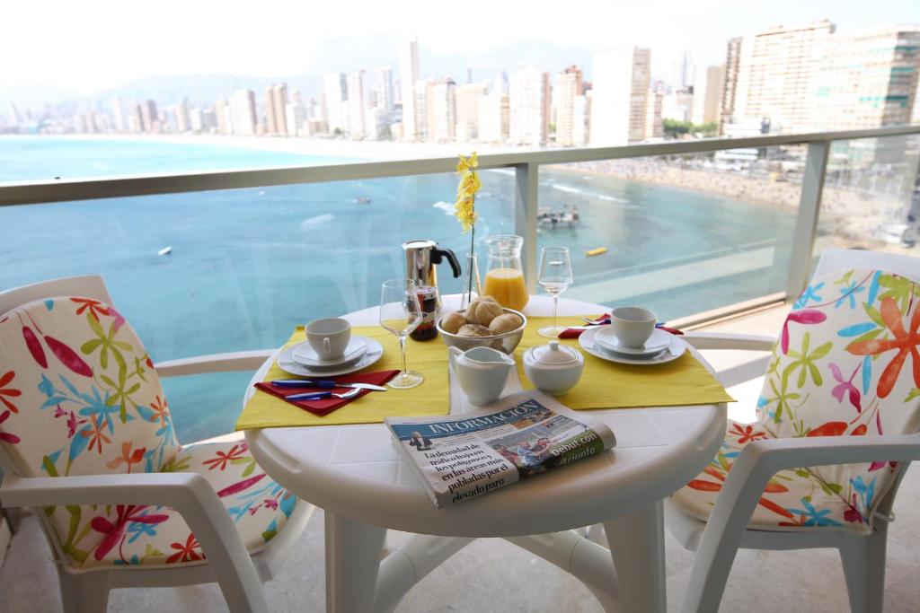 a table with a breakfast on a balcony with a view at Apartamentos Lido in Benidorm