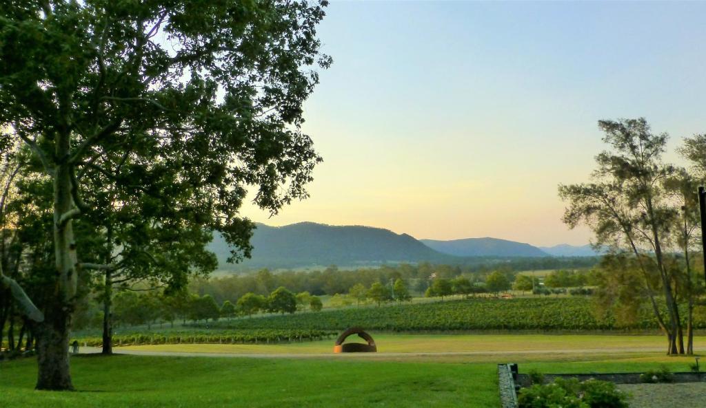 un parque con un árbol y un campo con montañas en Winmark Wines, en Broke