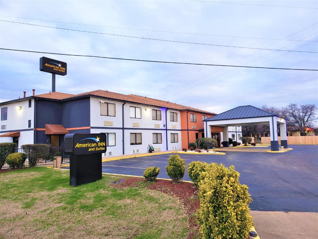 un hôtel avec un panneau devant un bâtiment dans l'établissement American Inn & Suites West Memphis, à West Memphis