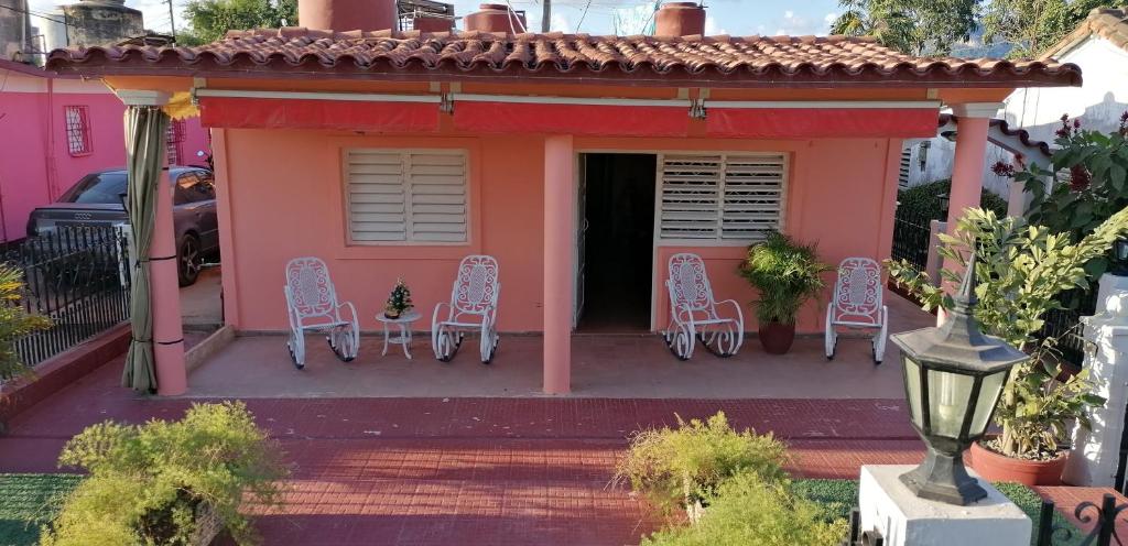 a pink house with chairs and a porch at El Campesino Yuri y Nino in Viñales
